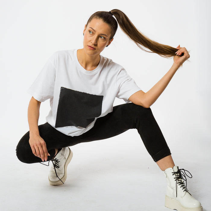 A female wearing a boxy white t-shirt with a black square printed in the front on artistic style