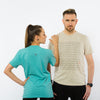 A female and a male in t-shirts in light brown and teal colours made of sustainable fabric. The front on the t-shirt is a geometric print made of many black shapes with only one red circle between them and with red Yulunga brand logo printed on the back.