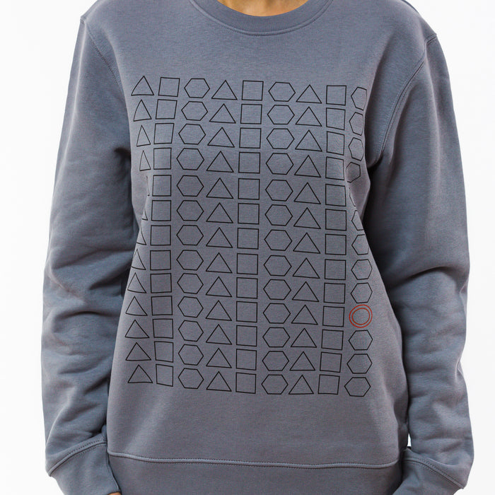 A person wearing a lavender grey colour sweatshirt made of  eco-friendly fabric with a geometric print made of  squares, triangles and hexagons in black but with one red circle in between them.