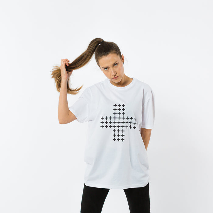 A female wearing a white organic cotton t-shirt with a print of a cross made of smaller black crosses in a minimalistic style