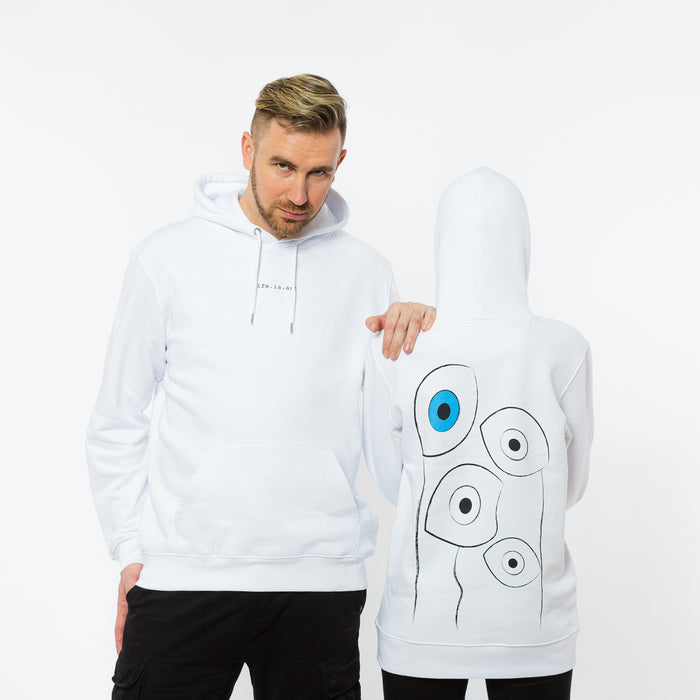 A male and a female wearing a white hooded sweatshirt with a sentence ,,Life. is. art" written in the front and a large abstract print of black and white eyes and one blue eye on the back. The garment is made of ethical fabric.