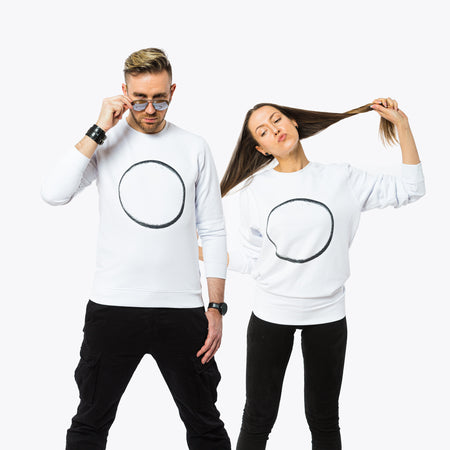 A male and a female wearing white sweatshirts with an image of a large black circle in minimalistic style