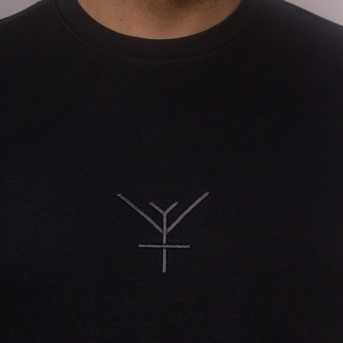 A close up on a black embroidery of Yulunga brand logo on a black organic cotton sweatshirt