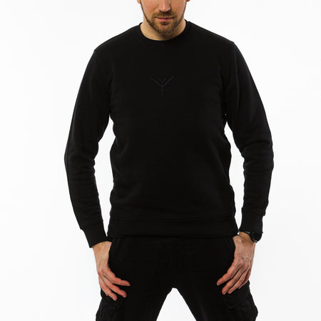 A male wearing a black organic sweatshirt with a black embroidery of Yulunga brand logo