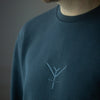 A close up on a dark grey unisex sweatshirt with a grey embroidery of a Yulunga brand logo