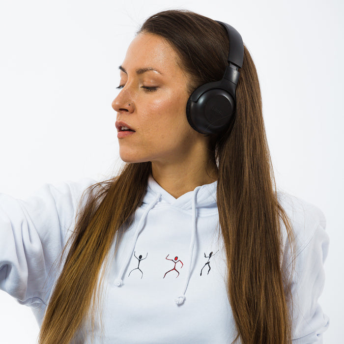 A female wearing a white hoodie with an image of three dancing silhouettes in a cave paintings style.