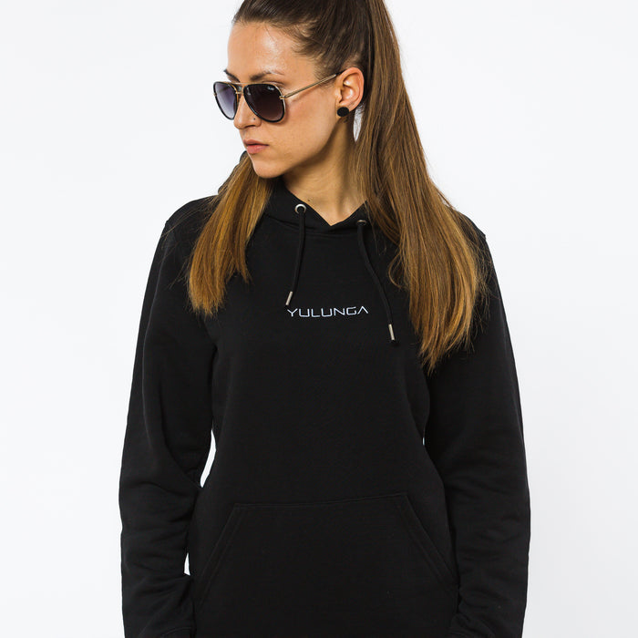 A female wearing a black organic cotton hoodie with a white Yulunga brand logo embroidered on the front