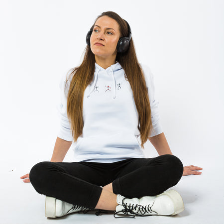 A female wearing a white organic cotton hoodie with an image of three dancing human silhouettes in black and red.