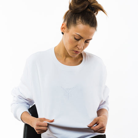 A female wearing a unisex plain white organic sweatshirt with a Yulunga brand embroidery