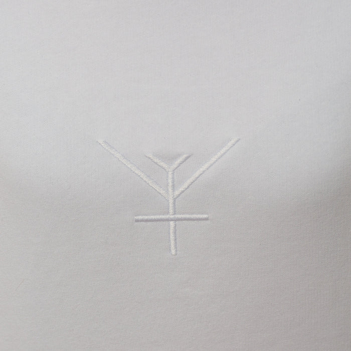 A close up on the Yulunga brand logo embroidery in white on a white hoodie