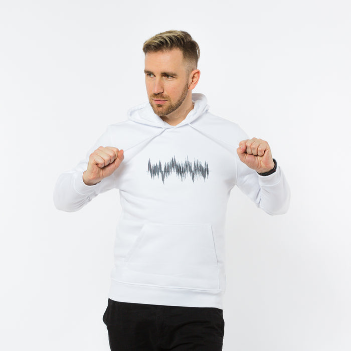 A male wearing a white hoodie with a black sound waves graphic in the front by Yulunga brand.